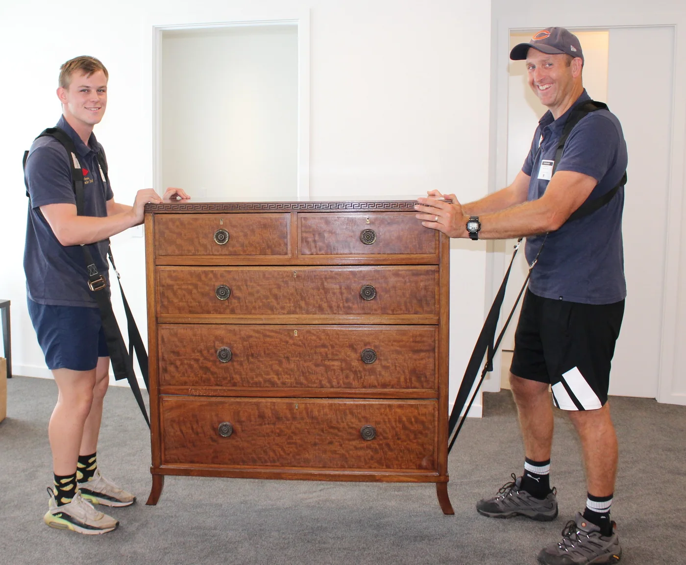 Two Bluebox movers carefully carrying a wooden chest